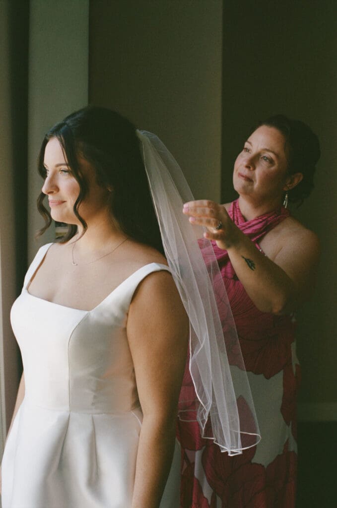 Mother helping bride put on veil before ceremony at the National Cathedral