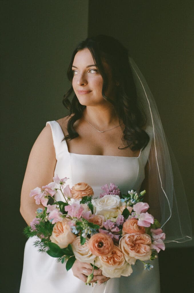 Bride standing by hotel window in wedding dress before cathedral wedding