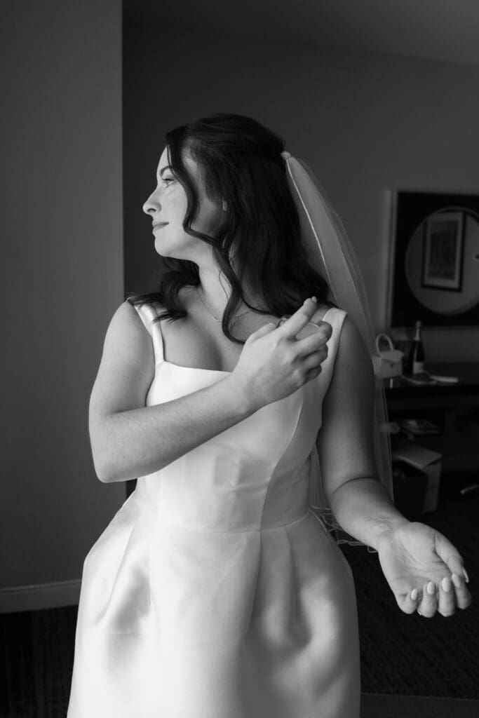 Bride standing by hotel window in wedding dress before cathedral wedding